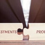 Businessman collects puzzles with the words Investments and profit