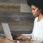 Portrait of young attractive African female blogger, typing a new challenging post during lunchtime