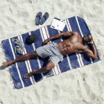 Young man relaxing on mat at beach