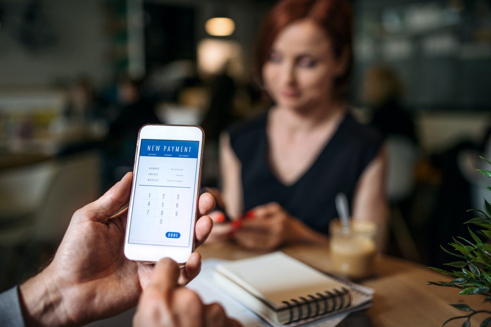 Midsection of businesspeople with smartphone in a cafe, checking finances.