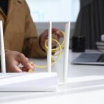 Close up view of man plugs internet cable into the router. Wireless internet concept.