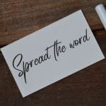 Top view of pen and memo note written with SPREAD THE WORD.