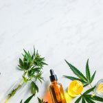 Various glass bottles with CBD oil, THC tincture hemp leaves on marble background Cosmetics CBD oil