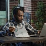 Sales consultant analyzing financial charts on papers and laptop