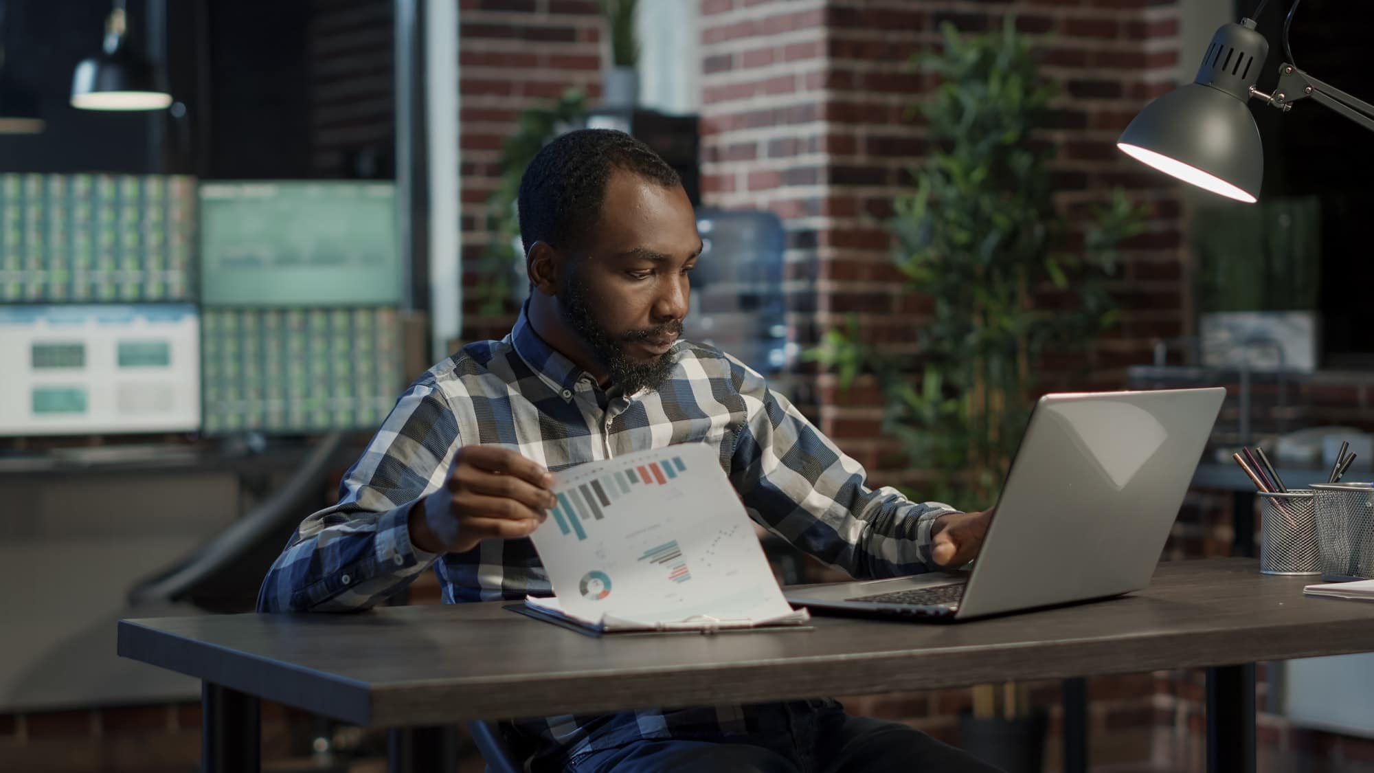 Sales consultant analyzing financial charts on papers and laptop