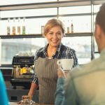 Experienced smiling barista making coffee to customers