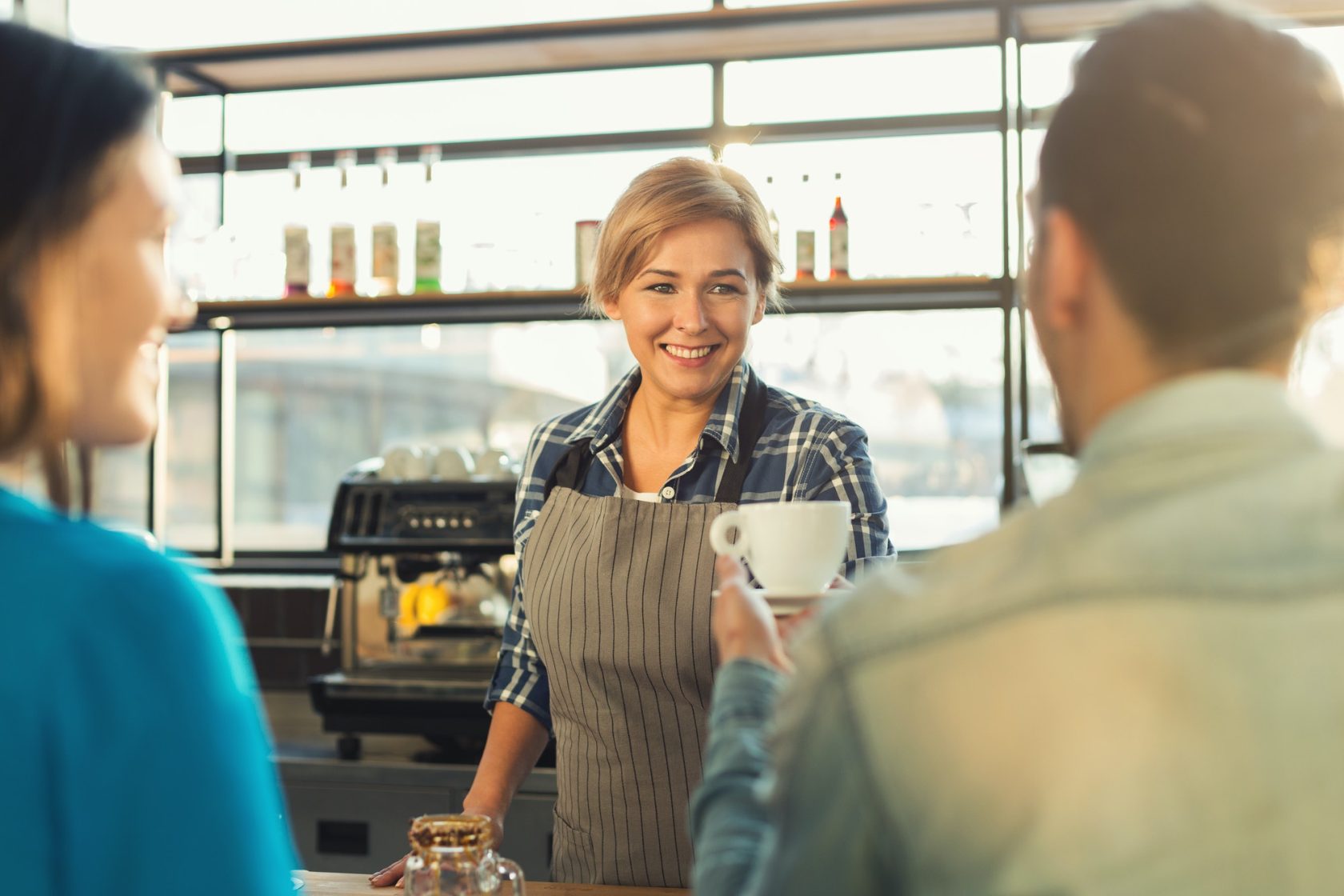Experienced smiling barista making coffee to customers