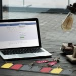 laptop with facebook website on table with macarons, coffee and sale tags in cafe