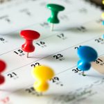 Thumb tack pins on calendar as reminder
