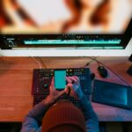 Male Video Editor sitting at his Computer using phone