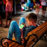 Boy playing games on his smartphone in the street