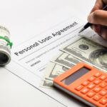 Filling up personal loan agreement form with a pen, calculator and fake money.