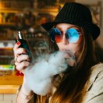 Vaping girl. Young hipster woman vape e-cig at the vapeshop. Hip-hop style. Closeup