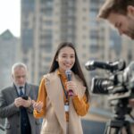 Young cute female reporter talking to a videocamera