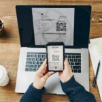 Woman scanning QR code from invoice to make payment using fast secure payment system and smartphone