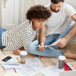 Family couple maintains home accounting, discuss plans and future payments, surrounded with bills on