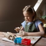 Little girl works with clay, kid in workshop
