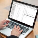 Email client list, woman hand on the computer laptop, inbox e mail message on the screen, close up