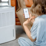 Woman sitting near air purifier and moisturizer appliance