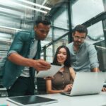 Searching for solutions. Group of three young and positive employees using modern technologies and