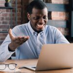 Young African man feels angry with errors or data leak he noticed on laptop screen