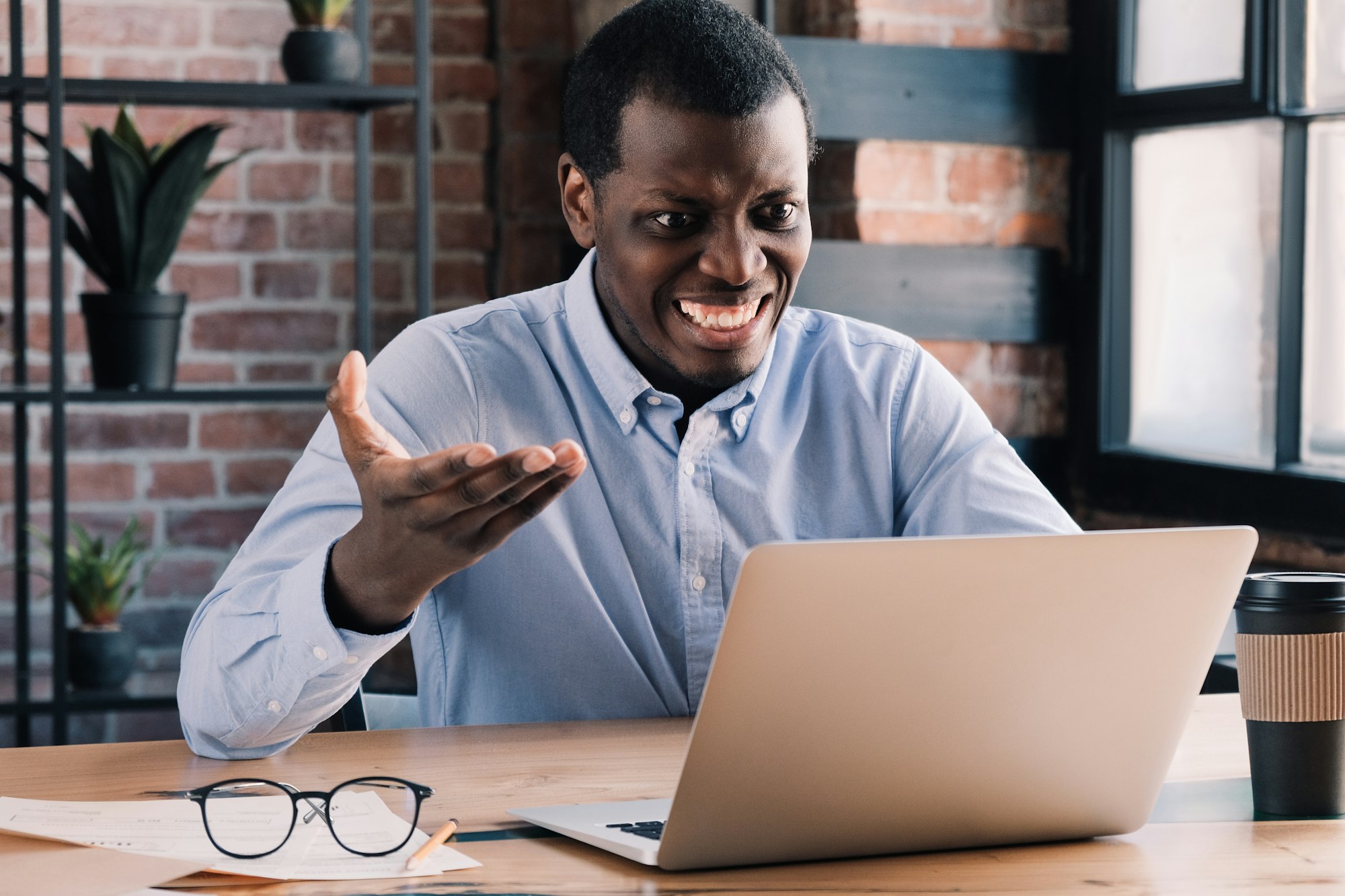 Young African man feels angry with errors or data leak he noticed on laptop screen